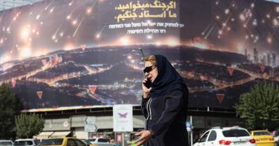 Mulher caminha em frente a um painel anti-Israel, no Irão.