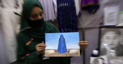 Mulher mostra pintura numa feira de ‘desenvolvimento económico e sucesso’ em Kabul.