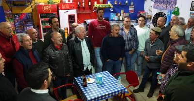 Elementos do Rancho de Cantadores da Aldeia Nova de São Bento cantam modas alentejanas no bar da sede do Clube Atlético Aldenovense, enquanto convivem, entre copos e petiscos.